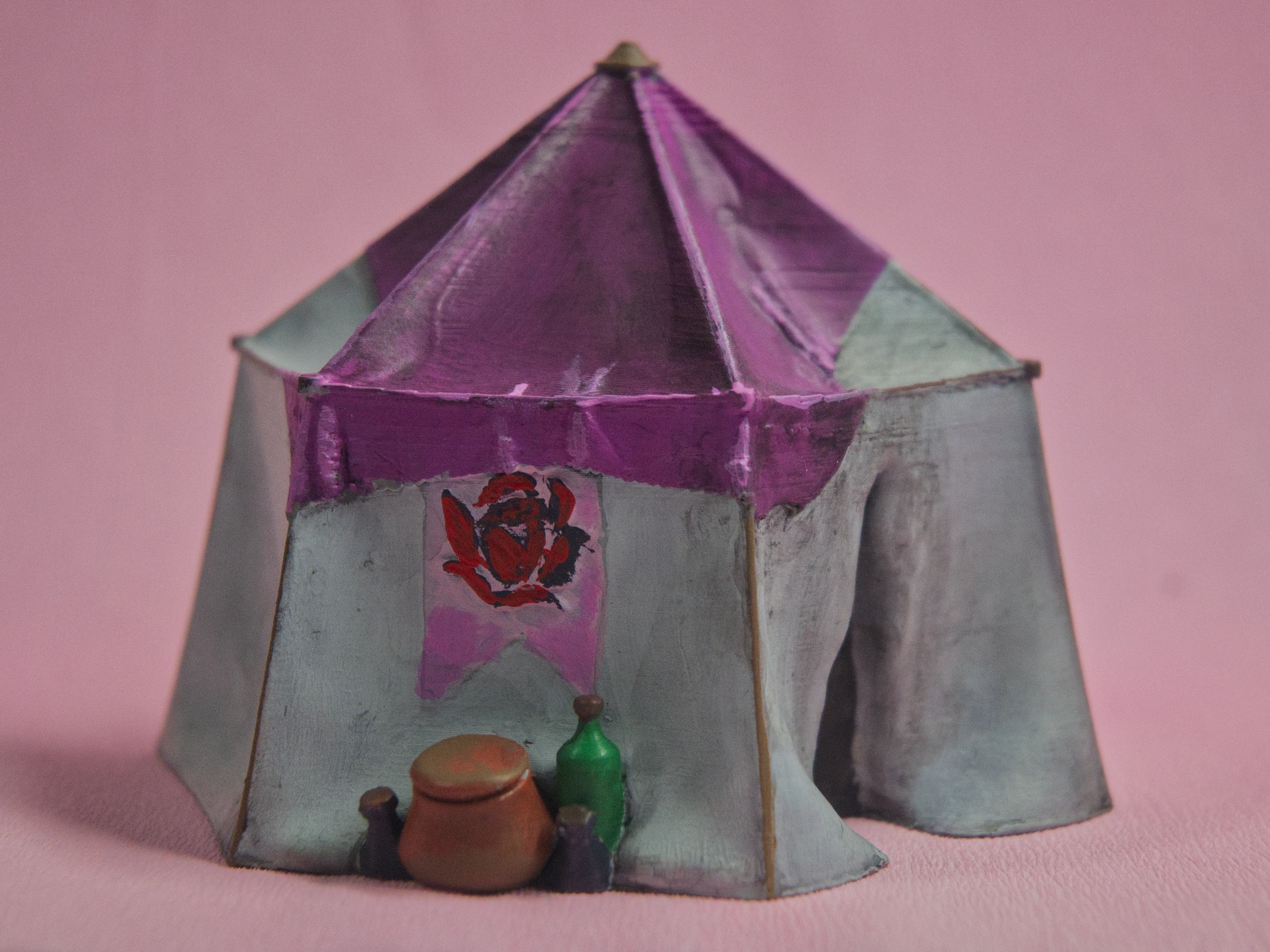 Ein großes sechs eck Zelt von der Seite mit weißen wänden Rosen Bannern und pinkem abdeck Tuch  